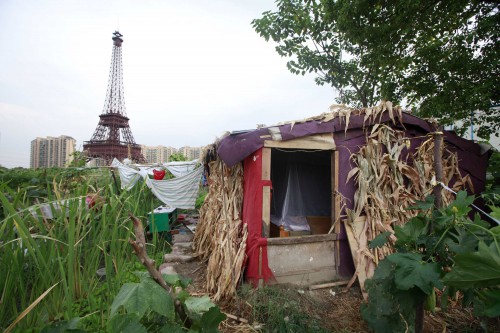A farmer's house is seen near a replica of the Eiffel Tower at the Tianducheng development in Hangzhou